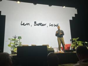 Presenter in front of a screen showing the words 'learn, better, local'